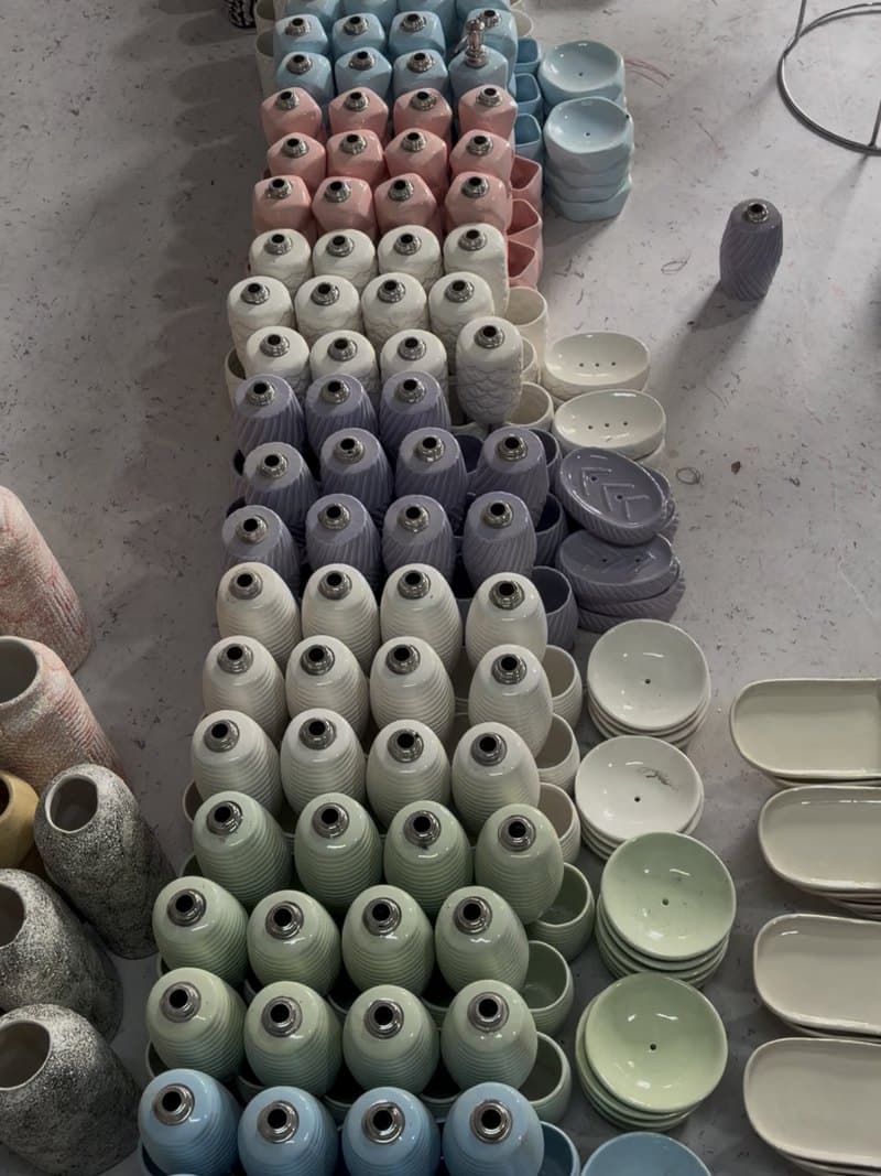 Rows of glazed ceramic pieces laid out by colour on the floor of the unit