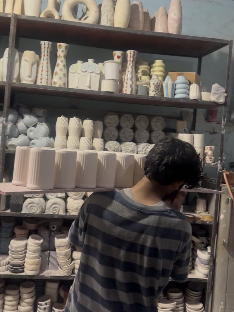 A maker sorting ceramic pieces at the shelves in the Khurja unit