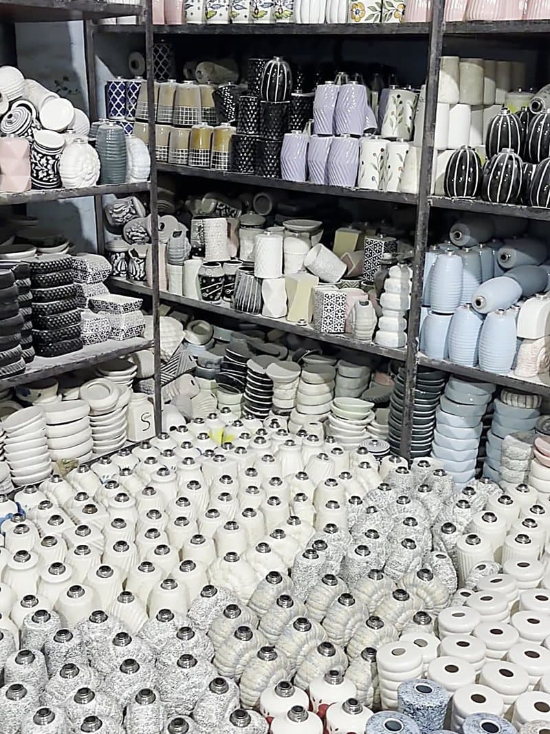Racks of glazed ceramic pieces in multiple colourways at the Khurja unit
